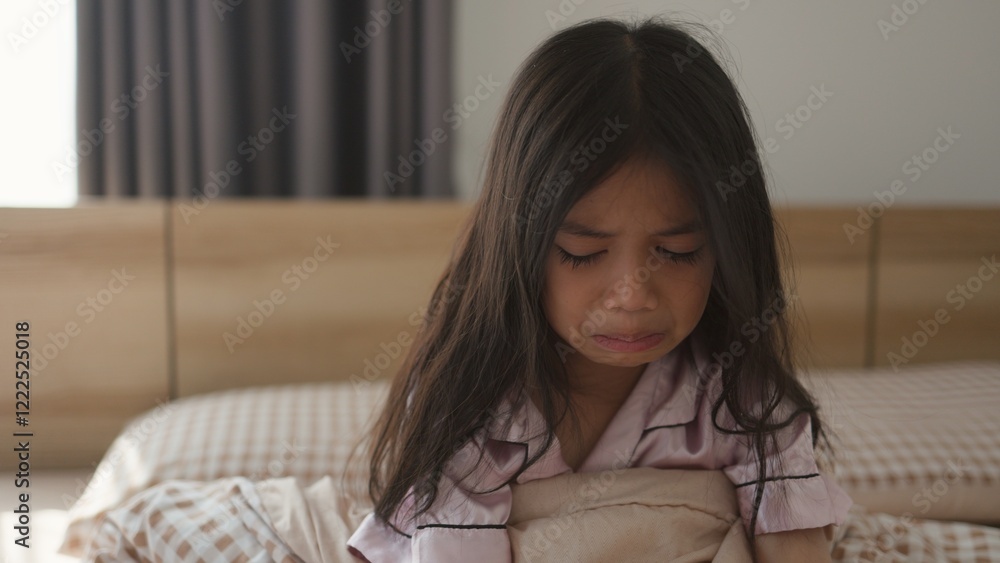 Naklejka premium The scared little girl in the bedroom crying with her hands holding her teddy in fear of monsters in darkness in the bedroom in the Child's nightmares imagination and psychological distress concept.