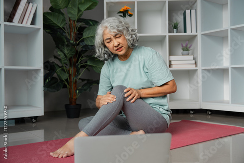 Senior woman experiencing knee discomfort while practicing wellness exercises at home photo