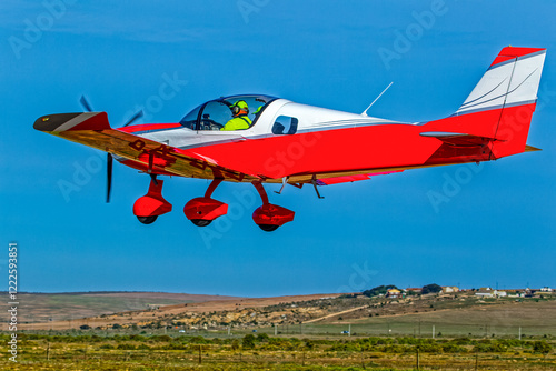 Fotografija Low flying bright red two-seater single engine aircraft at a small airfield in t