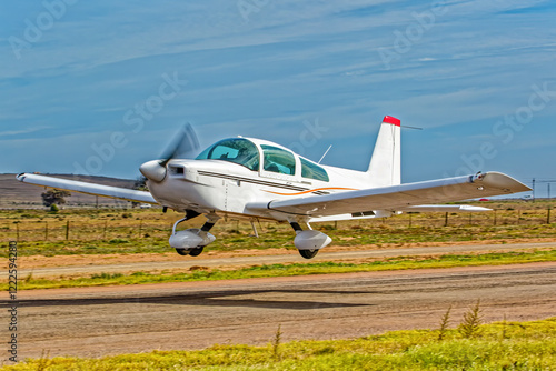 Powerful white and brown, low wing, single engine aircraft taking off from a small airfield in the Western Cape, South Africa