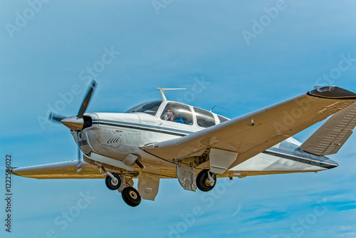 Six-seat white aircraft with black and blue stripes and retracting undercarriage and unique V shaped tail against blue sky in the Western Cape, South Africa