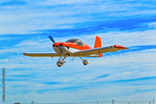 Bright red and white kit aircraft with fixed tricycle undercarriage flying against a blue cloudy sky in the Western Cape, South Africa