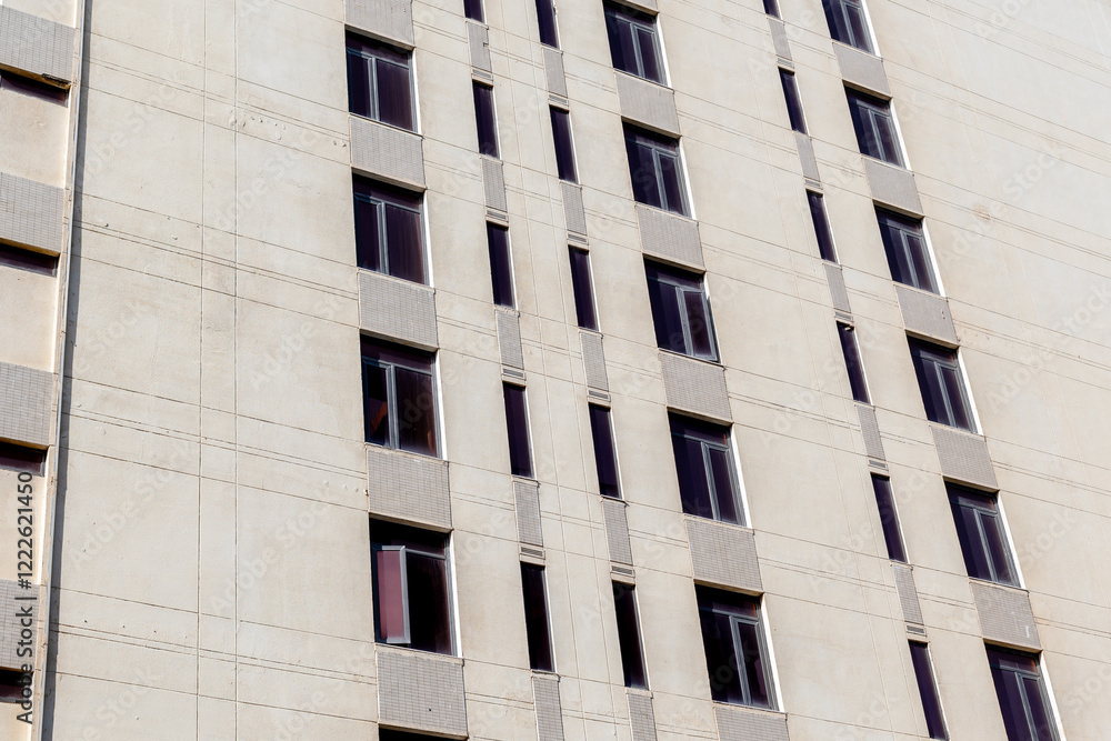 Beige building facade with repetitive windows pattern Beige building facade with repetitive windows pattern