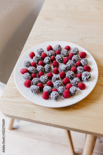 A plate of date balls and raspberries.