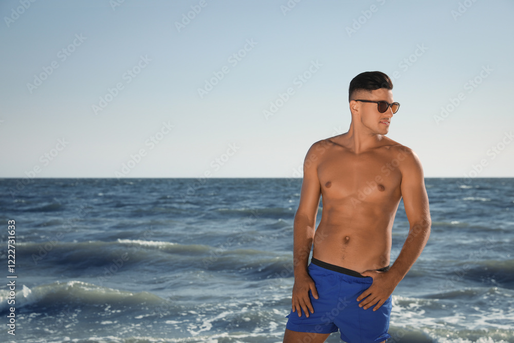 Handsome man with attractive body on beach. Space for text