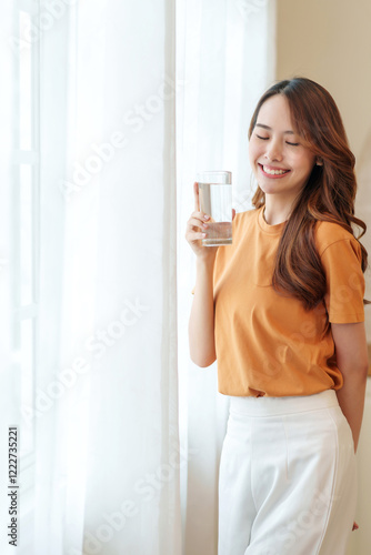 portrait smiling young woman with a glass of fresh water relaxing in the room,people with healthy lifestyle,health,beauty,health care