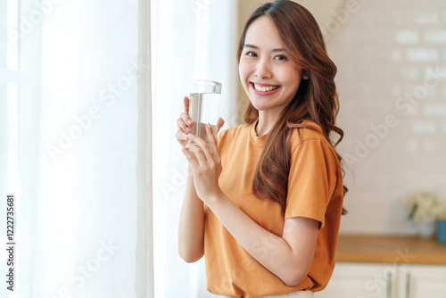 portrait smiling young woman with a glass of fresh water relaxing in the room,people with healthy lifestyle,health,beauty,health care