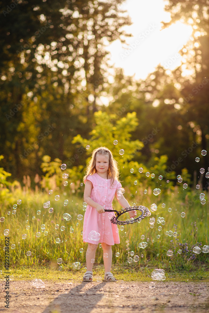 Naklejka premium Joyful girl on a sunny street surrounded by colorful soap bubbles, perfect for themes of summer, fun, childhood, play, and outdoor happiness