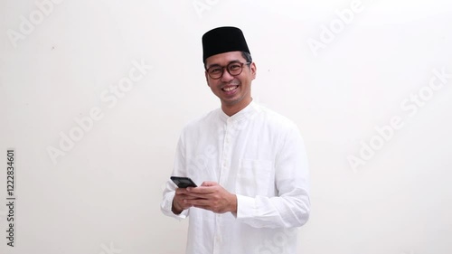 Asian muslim man smiling happy after typing on his mobile phone