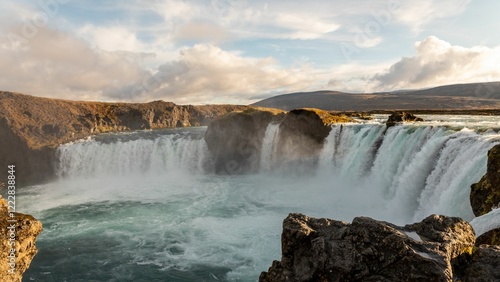 Breathtaking view of Godafoss waterfall in Iceland with mist rising under a partly cloudy sky