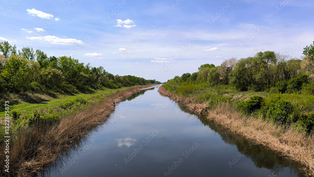 landscape by the river in the spring with sky and clouds reflected in the water landscape by the river in the spring with sky and clouds reflected in the water