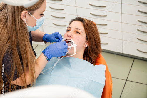 Photography Female dentist in protective mask and gloves performing a dental procedure on a