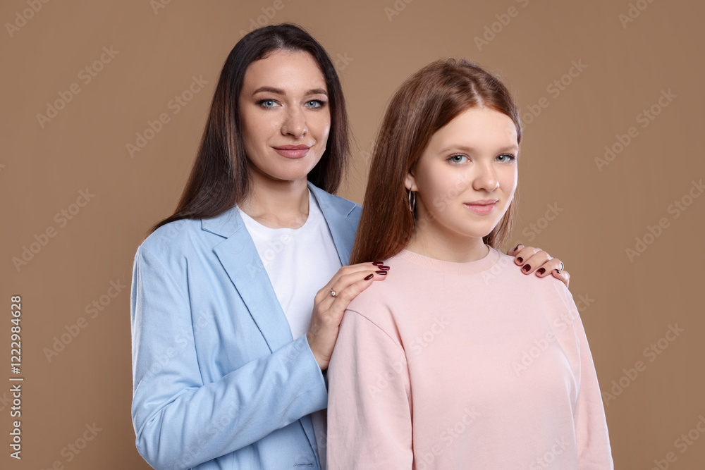 Portrait of beautiful mother with teenage daughter on dark beige background Portrait of beautiful mother with teenage daughter on dark beige background