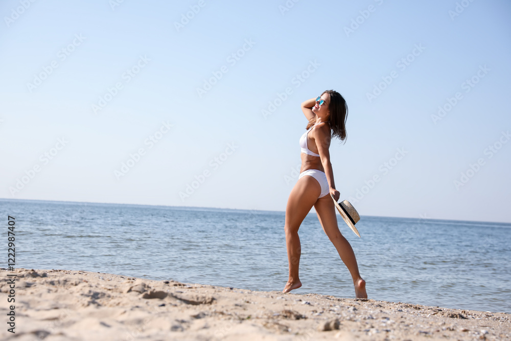 Fototapeta premium Young woman with beautiful body on sandy beach. Space for text