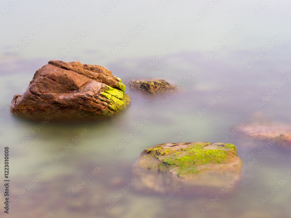Rocks in the sea crashing against soft waves Rocks in the sea crashing against soft waves