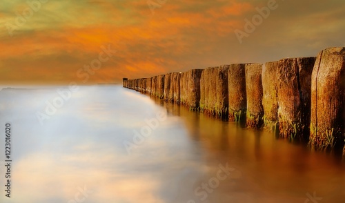 Fototapeta Naklejka Na Ścianę i Meble -  Golden hour on a groyne on the Baltic Sea beach