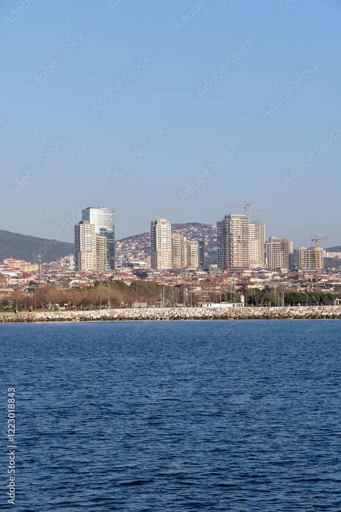 Obraz premium Skyline of Istanbul’s Asian side with modern residential buildings and a rocky shoreline. A vibrant view of the Anatolian side blending urban development and coastal beauty. Panaromic Istanbul 2025