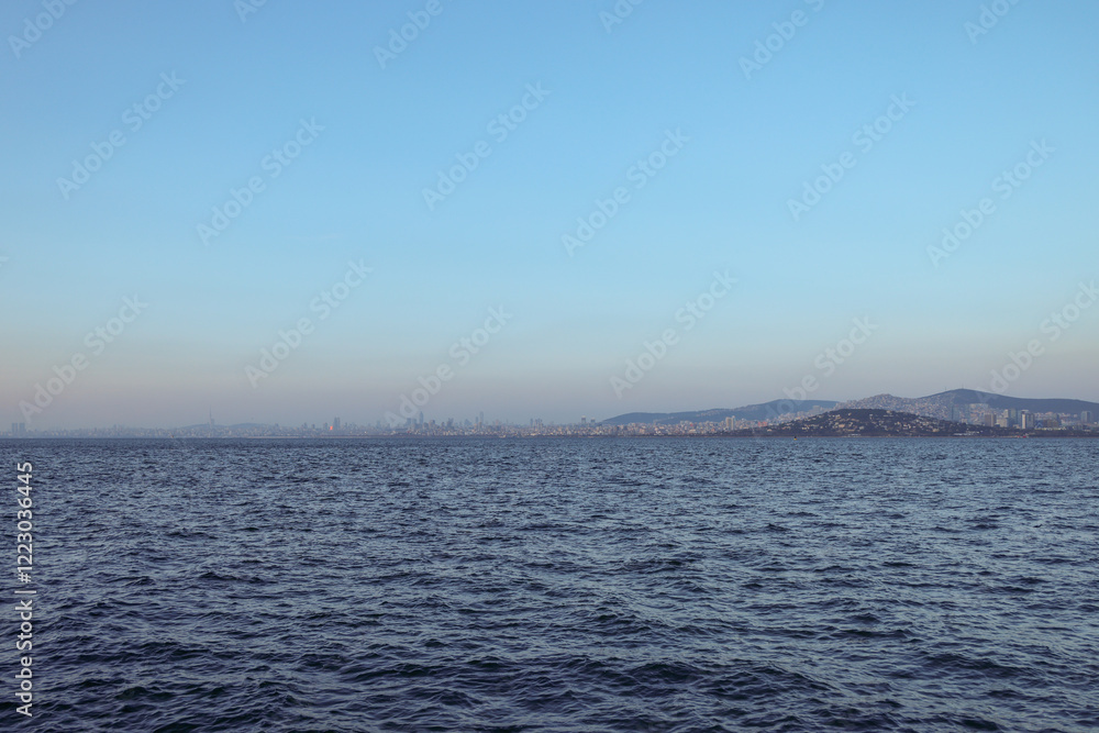 Distant view of Istanbul’s skyline and the Princes’ Islands from the Marmara Sea. The vast blue waters contrast with the urban landscape and rolling hills, creating a tranquil coastal scenery Distant view of Istanbul’s skyline and the Princes’ Islands from the Marmara Sea. The vast blue waters contrast with the urban landscape and rolling hills, creating a tranquil coastal scenery