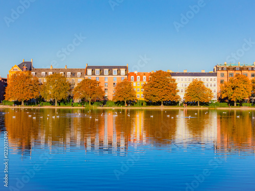 The golden hues of autumn paint the cityscape as the sun rises over Peblinge Sø, creating a peaceful and picturesque scene in Copenhagen, Denmark. photo