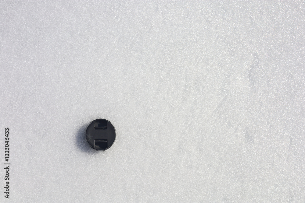 Camera lens plastic cover lying on the fresh snow surface Camera lens plastic cover lying on the fresh snow surface