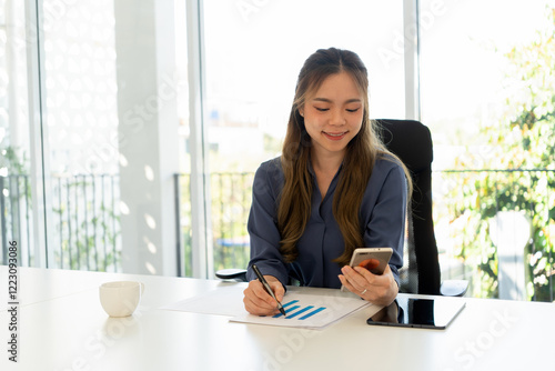 Businesswoman sitting at desk on couch in workplace or at home working on laptop and analyzing data on charts and graphs and writing on papers to make business plan and strategies for company. Free Download Businesswoman sitting at desk on couch in workplace or at home working on laptop and analyzing data on charts and graphs and writing on papers to make business plan and strategies for company. - GFXLoad