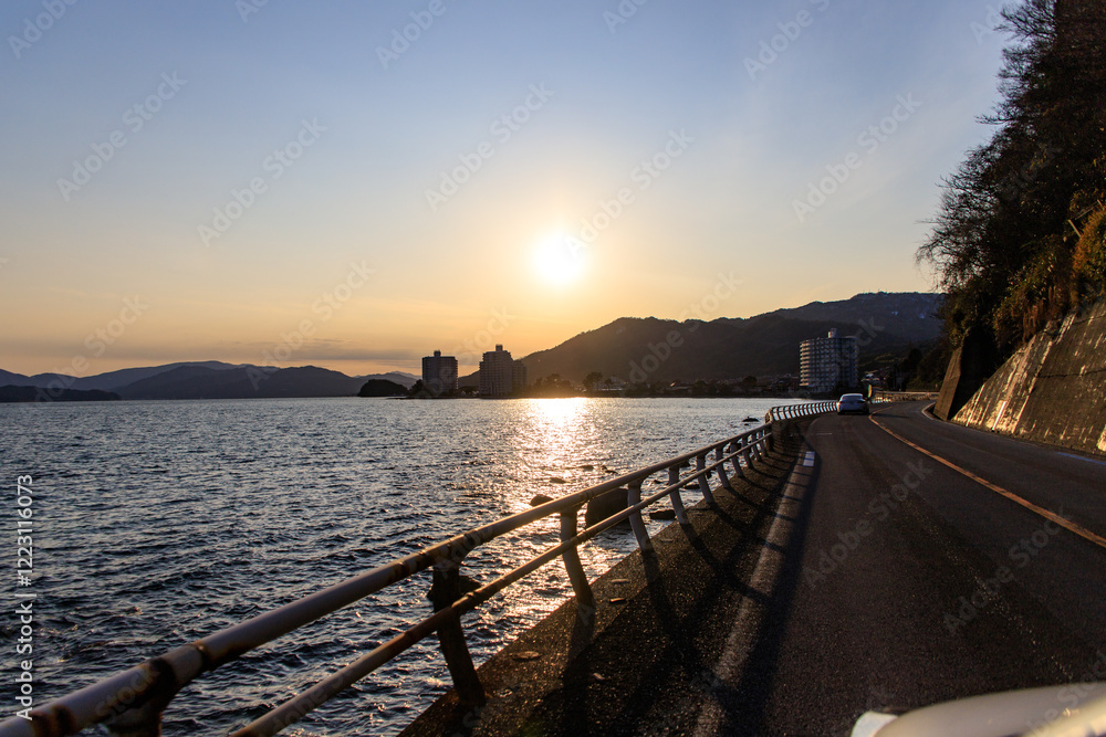 Coastal Road Leading to Distant Cityscape at Sunset Coastal Road Leading to Distant Cityscape at Sunset