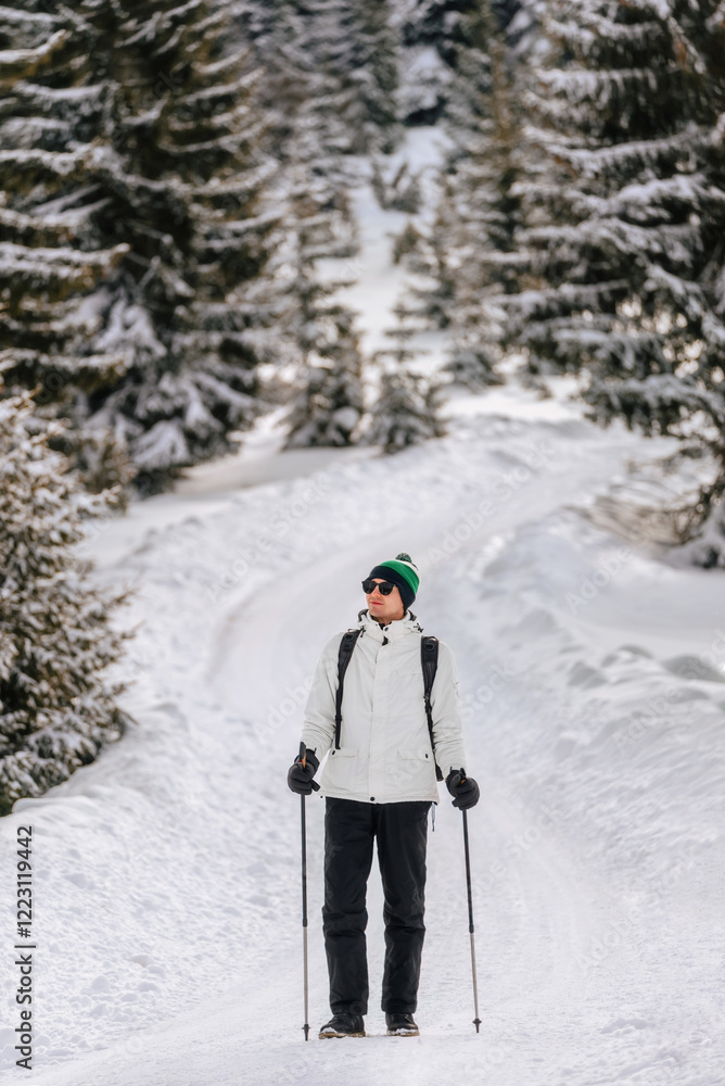 Man Hiking with Trekking Poles in Snow Forest