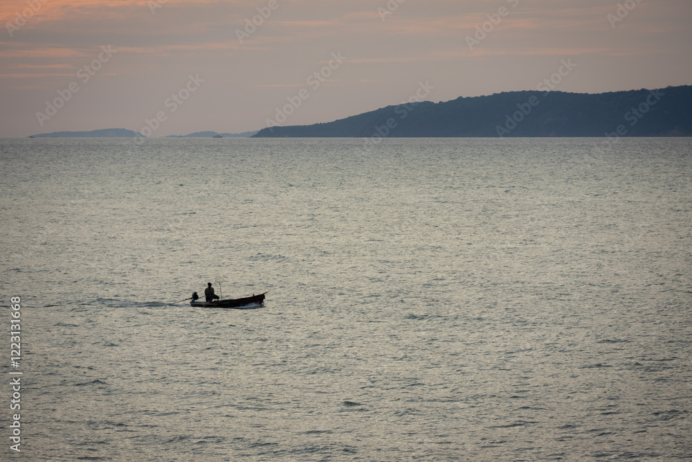Naklejka premium silhouette lone boat cuts through the calm waters as the sun begins its descent, casting a warm glow across the horizon