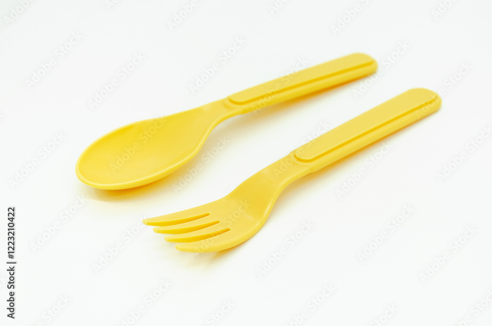 Yellow plastic picnic spoon and fork on white background, copy space