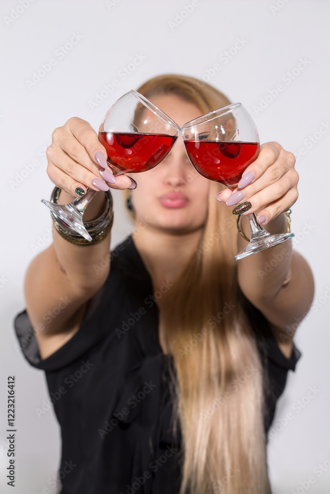 A woman is holding two wine glasses and making a face