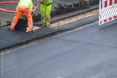 Konzept Glasfaserausbau, Internet, Kommunikation und: Arbeiter bei Baumaßnahmen für die Verlegung von Glasfaserleitungen für den Hausanschluss in einer Straße