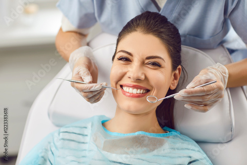 Quadro su tela Portrait of a smiling patient with dentist doctor is checking teeth with a dental instrument
