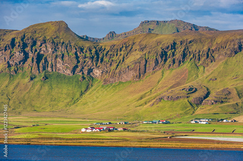 Majestic Icelandic mountains overlook quaint buildings nestled in lush green landscape photo