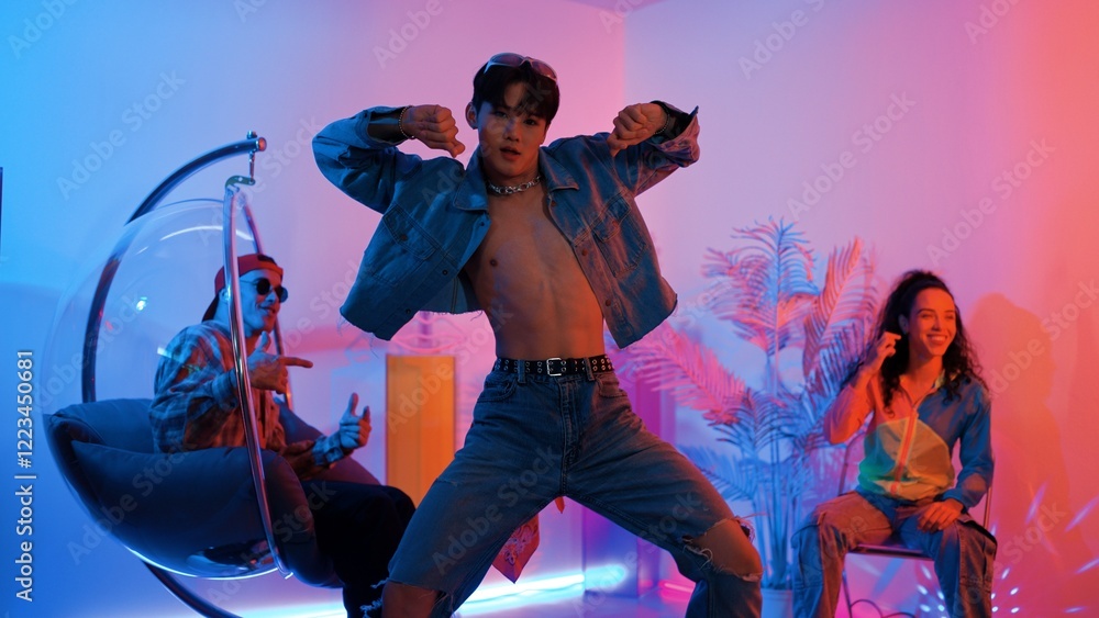 Fototapeta premium Skilled asian dancer moving to modern music while multicultural friend sitting at chair. Professional performer dancing show energetic foot step while hipster team cheering and supporting. Regalement.