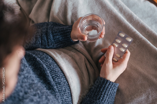 Man holding water and pills. Daily medication routine. Health care treatment for flu, cold, virus