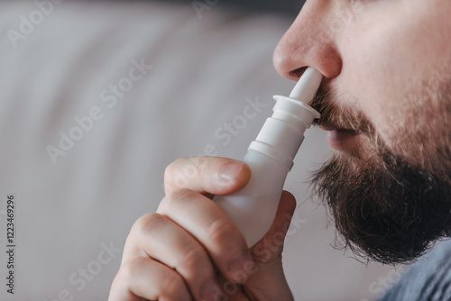 Man using a nasal decongestant spray with copy space. Nasal spray to relieve congestion, Rhinitis, medicine and healthcare concept. close-up view