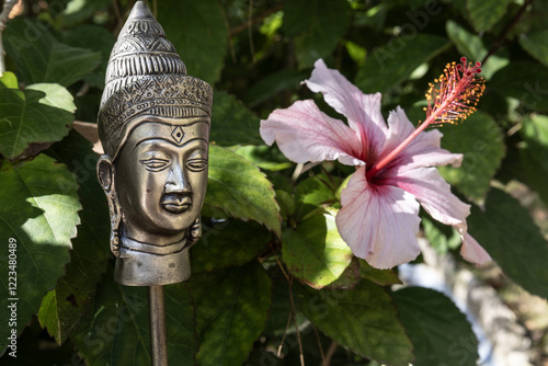 Buddha statue in green bush leaves with pink flower. Vesak day, Purnima, spring flowers festival, Songkran. Background, copy space, text place photo