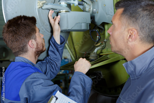 turner operates on a mechanical lathe with apprentice photo