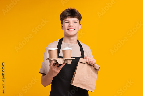 Fotografie Teenage boy with order working as cashier on orange background