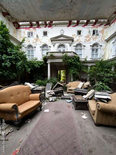 A decrepit mansion with peeling paint and overgrown garden lies in disarray, furniture overturned and belongings scattered everywhere, disarray, decayed interior photo