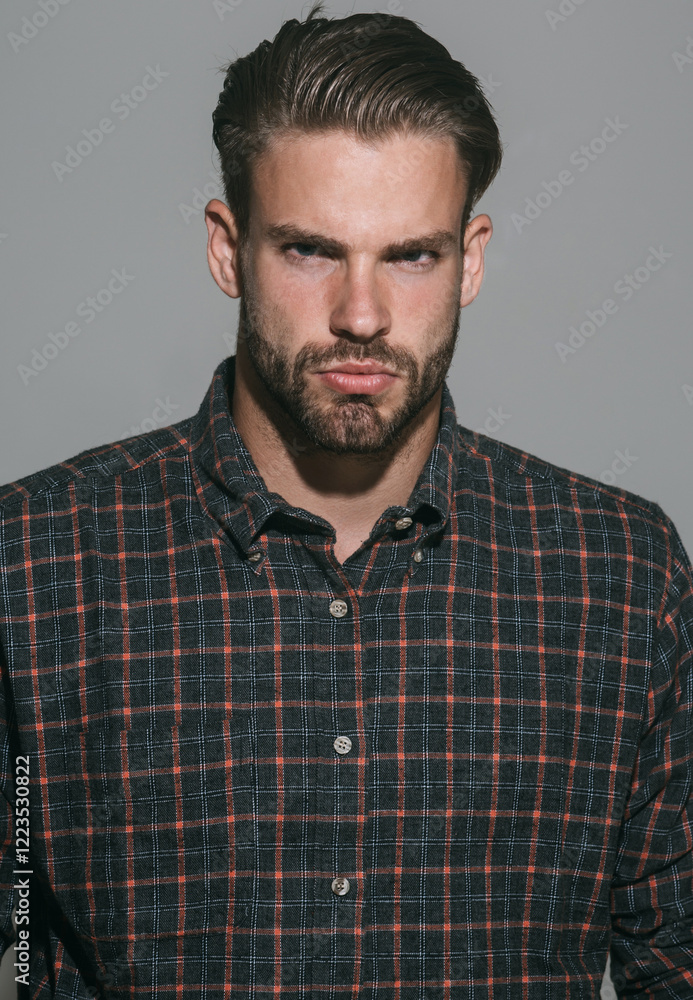 Fototapeta premium Man portrait. Closeup portrait of serious unshaven man in checkered shirt. Sexy male model with stylish hairstyle in plaid shirt. Handsome bearded guy in casual clothes. Fashionable guy with beard.