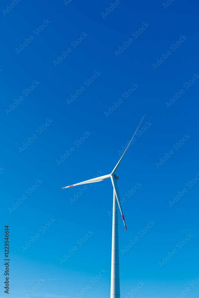 Wind energy generation. Electricity is generated by a wind turbine against a blue sky. Sustainable energy production in a windy green zone. Ecological energy generation Wind energy generation. Electricity is generated by a wind turbine against a blue sky. Sustainable energy production in a windy green zone. Ecological energy generation