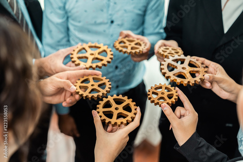 Group of multiracial business people joining gear wheels together as effective unity and productive teamwork concept. Efficient system business team process for solution solving. Meticulous