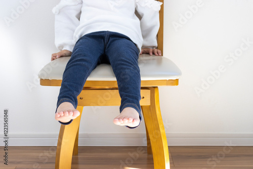 Obraz na płótnie 大きい椅子に座る女の子の脚(日本人、4歳、顔無し) w salonie