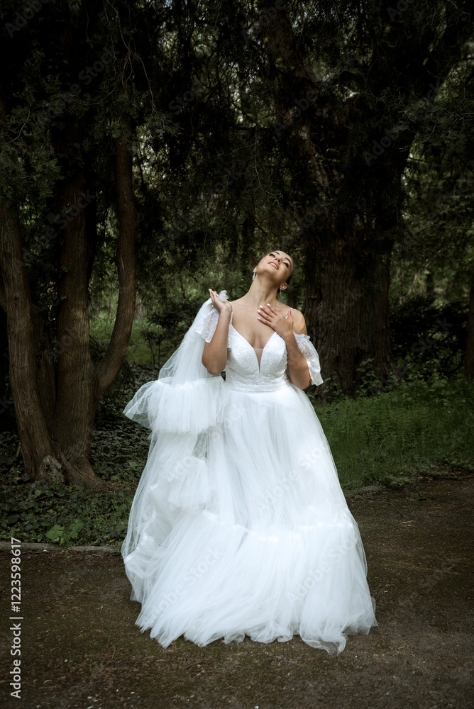 bride in white dress and long veil stands among trees. bride in white dress and long veil stands among trees.