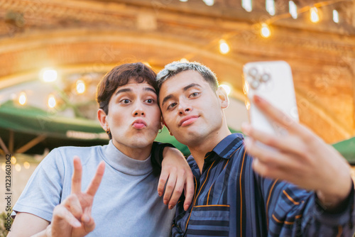 Young gay latin friends taking a selfie with a phone outside, generation z