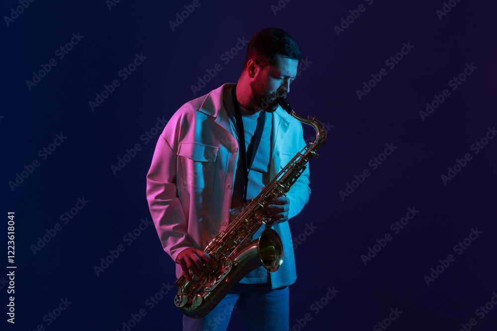 Naklejka premium Professional musician playing saxophone on color background with neon lights