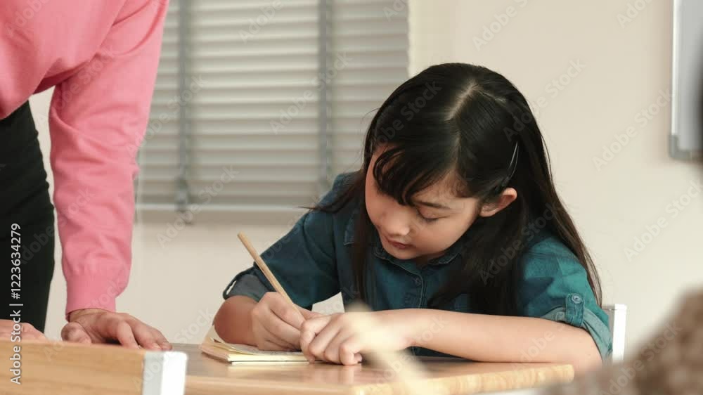Asian girl writing or taking a note while teacher checking classwork. Caucasian teacher help happy student doing test or classwork while diverse student study in science lesson. Education. Pedagogy. Asian girl writing or taking a note while teacher checking classwork. Caucasian teacher help happy student doing test or classwork while diverse student study in science lesson. Education. Pedagogy.