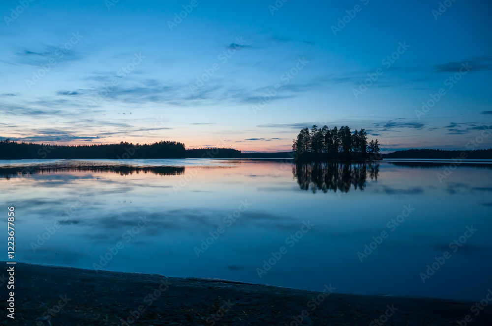 Late evening scenery of a calm lake with a wooden island in the forests of Finland Late evening scenery of a calm lake with a wooden island in the forests of Finland