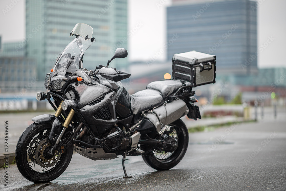 A large black touring motorcycle is covered in snow. The end of the motorcycle season, winter. The inscriptions A large black touring motorcycle is covered in snow. The end of the motorcycle season, winter. The inscriptions